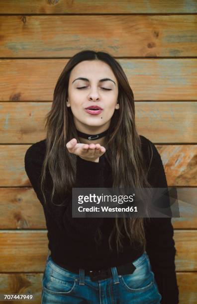 portrait of young woman with eyes closed blowing a kiss to viewer - blowing a kiss imagens e fotografias de stock