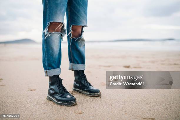 woman wearing boots and torn jeans on the beach, partial view - woman boots fotografías e imágenes de stock