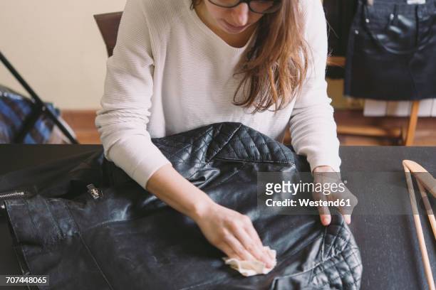 woman cleaning leather jacket - leather jacket stockfoto's en -beelden
