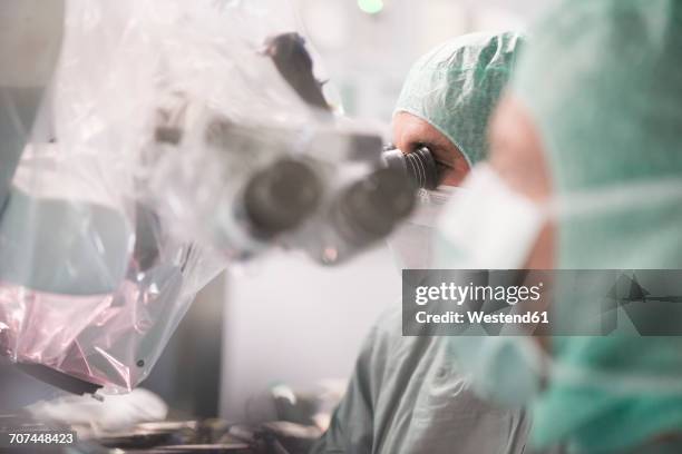 neurosurgeon looking through microscope during an operation - neurosurgeon stock pictures, royalty-free photos & images