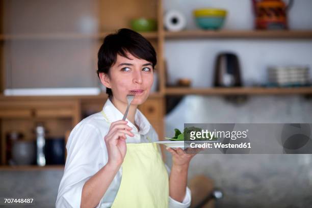 portrait of young woman tasting salad in the kitchen - solo una donna giovane foto e immagini stock