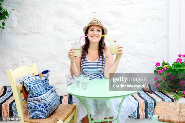 woman drinking two mojitos sitting in a bar outdoors - holding two things foto e immagini stock