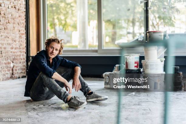 man sitting on floor in unfinished room - fundador fotografías e imágenes de stock