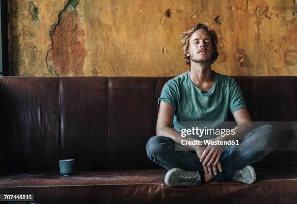 man sitting on couch in unfinished room - occhi chiusi foto e immagini stock