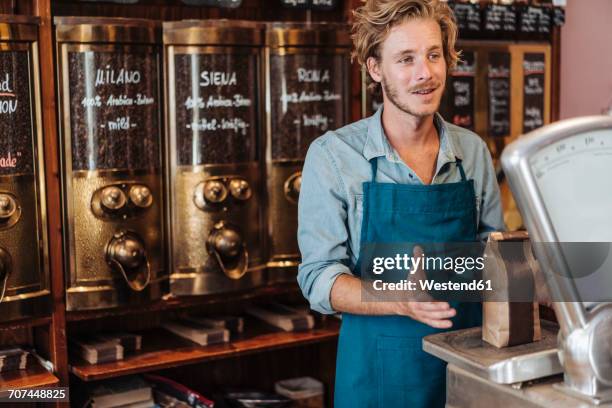 coffee roaster weighing coffee in his shop - busy coffee shop stockfoto's en -beelden