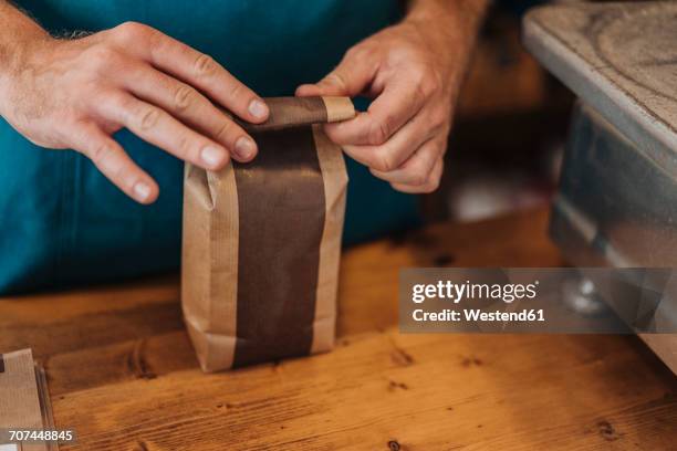 close-up of man packing bag of coffee at shop counter - coffee bag stock-fotos und bilder