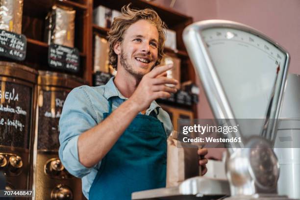 coffee roaster weighing coffee in his shop - busy coffee shop stockfoto's en -beelden