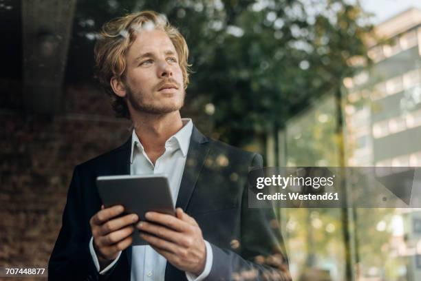 businessman with tablet looking away - mann busines fenster stock-fotos und bilder