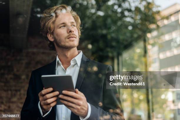businessman with tablet looking away - well dressed young man stock pictures, royalty-free photos & images