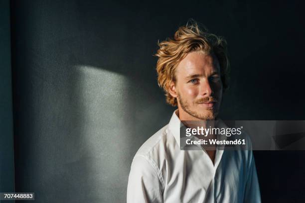 portrait of smiling blond man wearing white shirt - un solo hombre joven fotografías e imágenes de stock