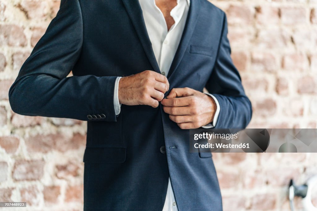 Close-up of of businessman buttoning jacket