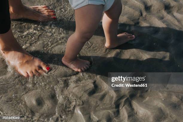 mother with little daughter wading in water on the beach - mother and child in water at beach stock pictures, royalty-free photos & images