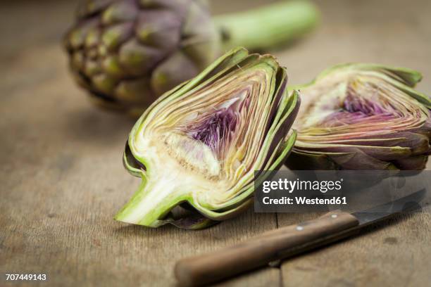 sliced artichoke and kitchen knife on wood - artichoke stock pictures, royalty-free photos & images