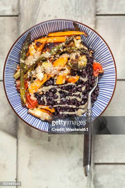 vegan buddha bowl of black rice, roasted vegetables, tahini sauce and sesame seeds - buddha bowl stockfoto's en -beelden