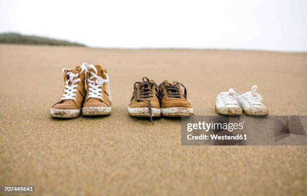 three pairs of shoes with different sizes on the beach - uitkleden stockfoto's en -beelden