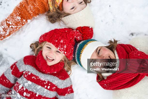 mother and daughters lying on snow, having fun - day 6 stock-fotos und bilder
