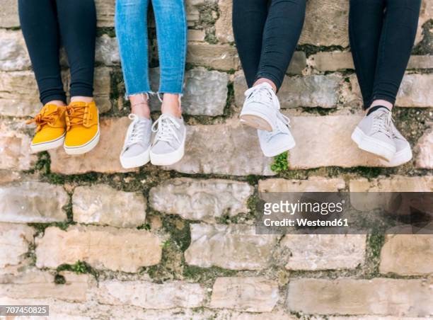 legs of four friends sitting side by side on a wall - shoes in a row stock pictures, royalty-free photos & images