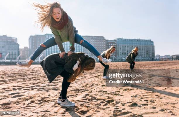 four friends playing leapfrog on the beach - junge frau strand sand springen stock-fotos und bilder