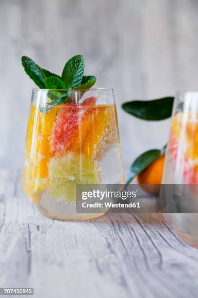 two glasses of detox water infused with citrus fruits - sparkling water photos et images de collection