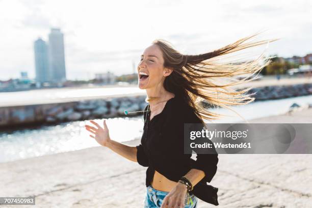 exuberant young woman at the seafront - blown away tour stock pictures, royalty-free photos & images