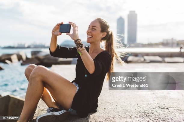 happy young woman looking at cell phone at the seafront - barcelona free stockfoto's en -beelden