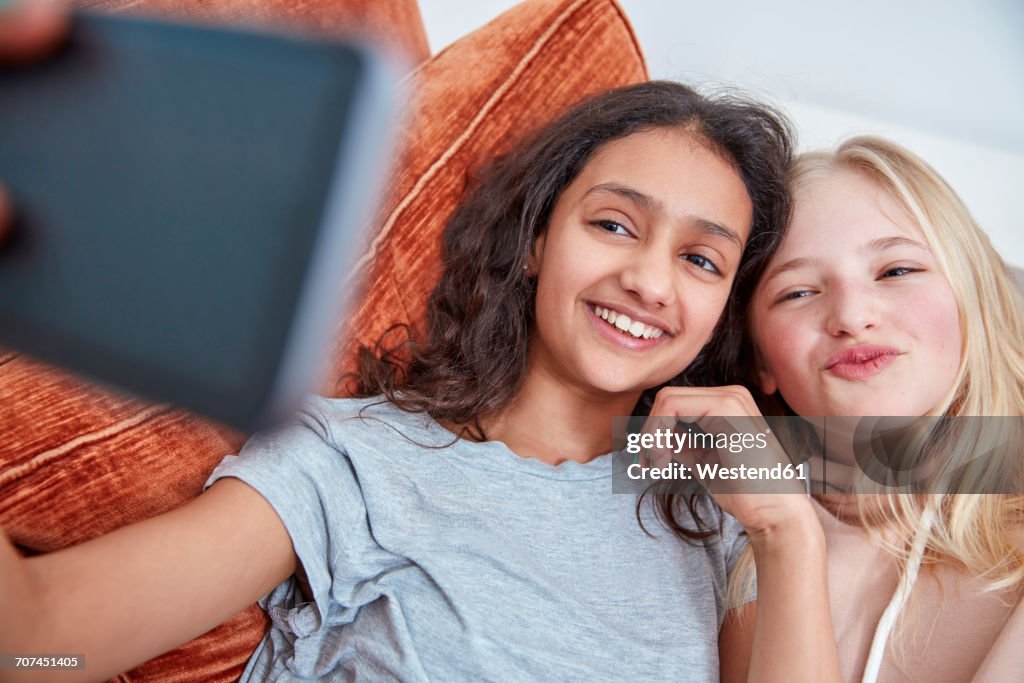 Two happy girls on couch taking a selfie