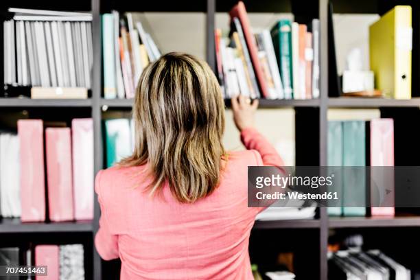 rear view of businesswoman at bookshelf - frau aktenordner stock-fotos und bilder