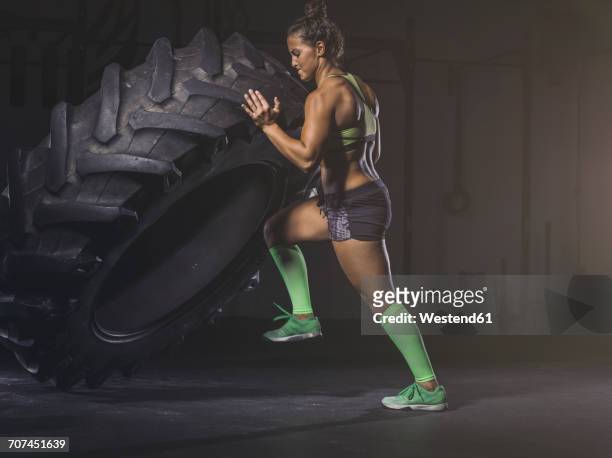 young woman lifting up a tractor tyre - tyre side view foto e immagini stock