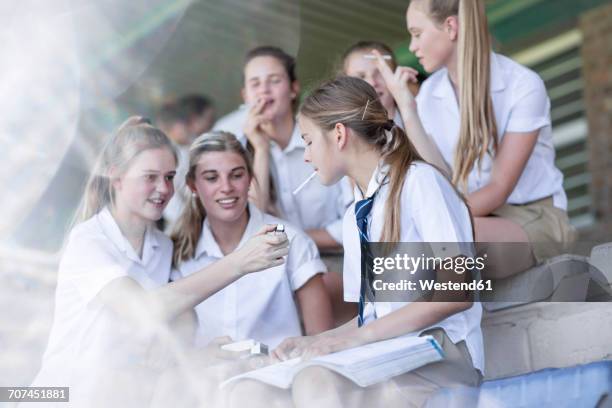 female high school students smoking a cigarette - alleen tienermeisjes stockfoto's en -beelden