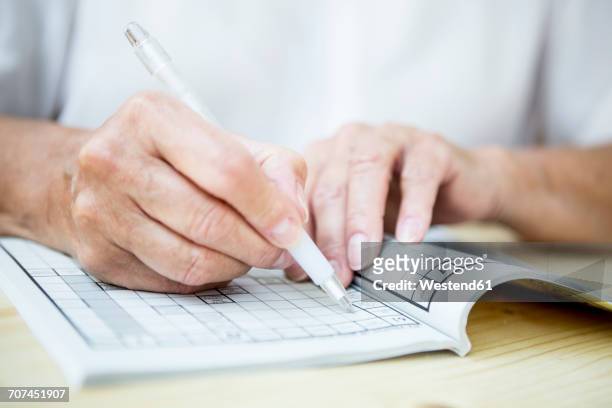 close-up of senior woman doing a crossword puzzle - teaser stock pictures, royalty-free photos & images