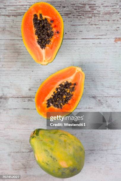 whole and sliced papaya on wood - papaya stock-fotos und bilder