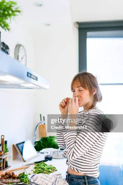 young woman cooking vegan pasta in her kitchen - smelling food stock pictures, royalty-free photos & images