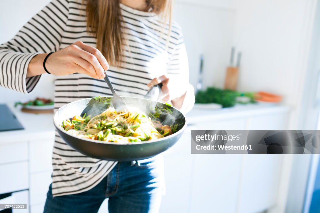 Young woman holding pan with vegan pasta dish