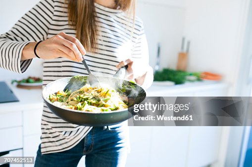 Young woman holding pan with vegan pasta dish Young woman holding pan with vegan pasta dish