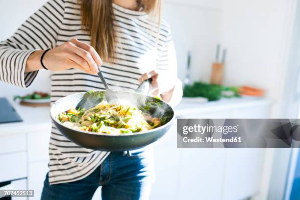 young woman holding pan with vegan pasta dish - cozinhando - fotografias e filmes do acervo