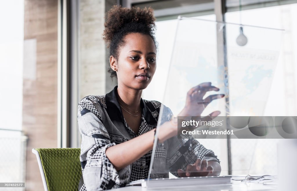 Young woman working in office using transparent computer