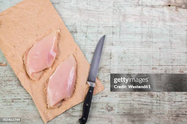 chicken breast on brown paper and a knife - kipfilet stockfoto's en -beelden