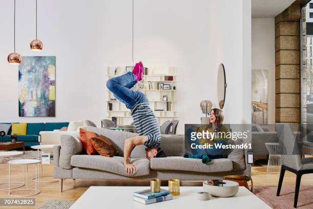 couple in modern furniture store doing headstand on couch - headstand ストックフォトと画像