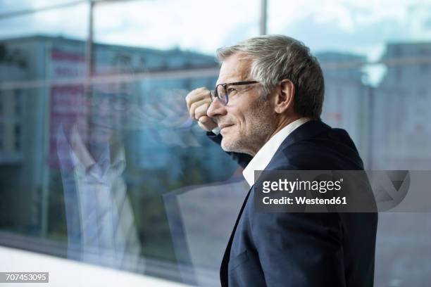 confident businessman looking out of window - sehen stock-fotos und bilder