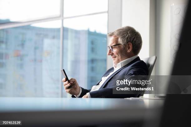 businessman using cell phone in office - geschäftsmann im büro mobiltelefon stock-fotos und bilder