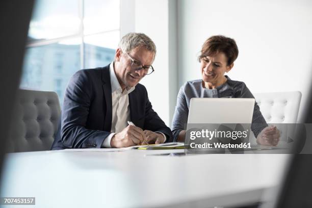 businessman and businesswoman working together in office - 50s woman writing at table imagens e fotografias de stock