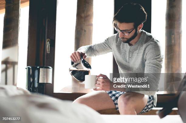 young man pouring coffee into cup at home - coffee pot stock pictures, royalty-free photos & images