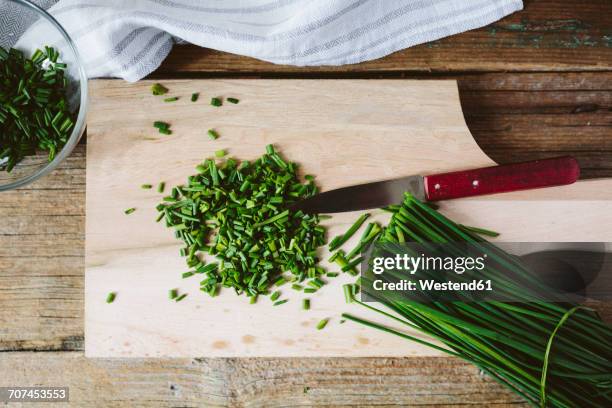 chopped and whole chives and kitchen knife on wooden board - cebolinho imagens e fotografias de stock
