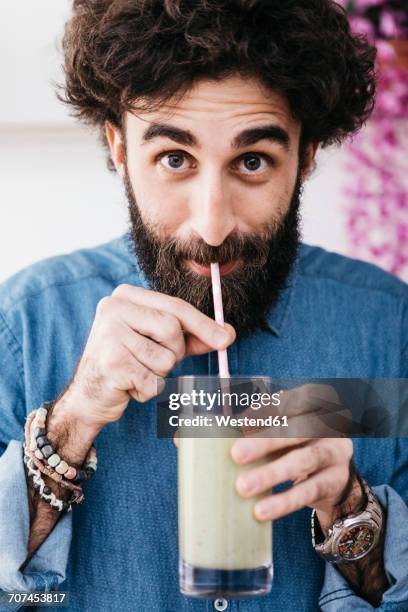 portrait of bearded man drinking green smoothie - straw foto e immagini stock