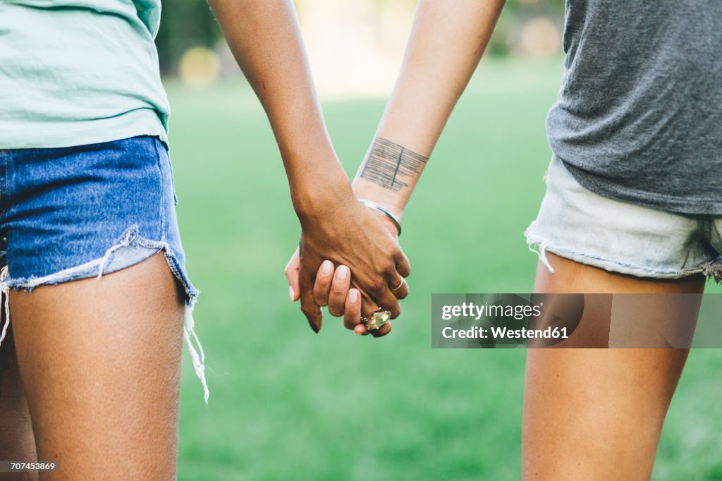 Two women holding hands in a park