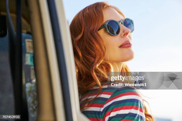 young woman wearing sunglasses leaning against car - junge frau allein stock-fotos und bilder