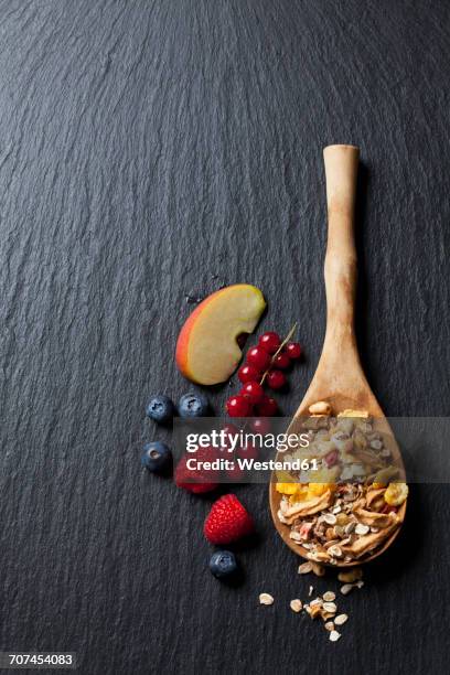 wooden spoon of granola with dried fruits and various fresh fruits on slate - schist stock-fotos und bilder