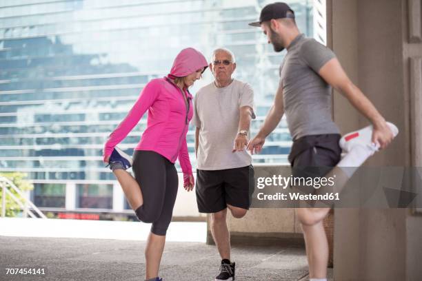three athletes stretching in the city - 3 old men jogging stock-fotos und bilder