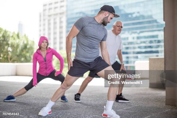 three athletes stretching in the city - 3 old men jogging stockfoto's en -beelden