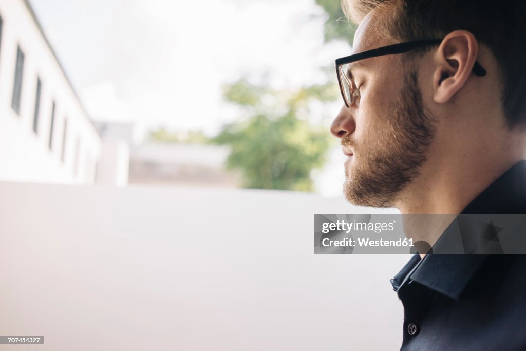 Serious man with closed eyes at the window